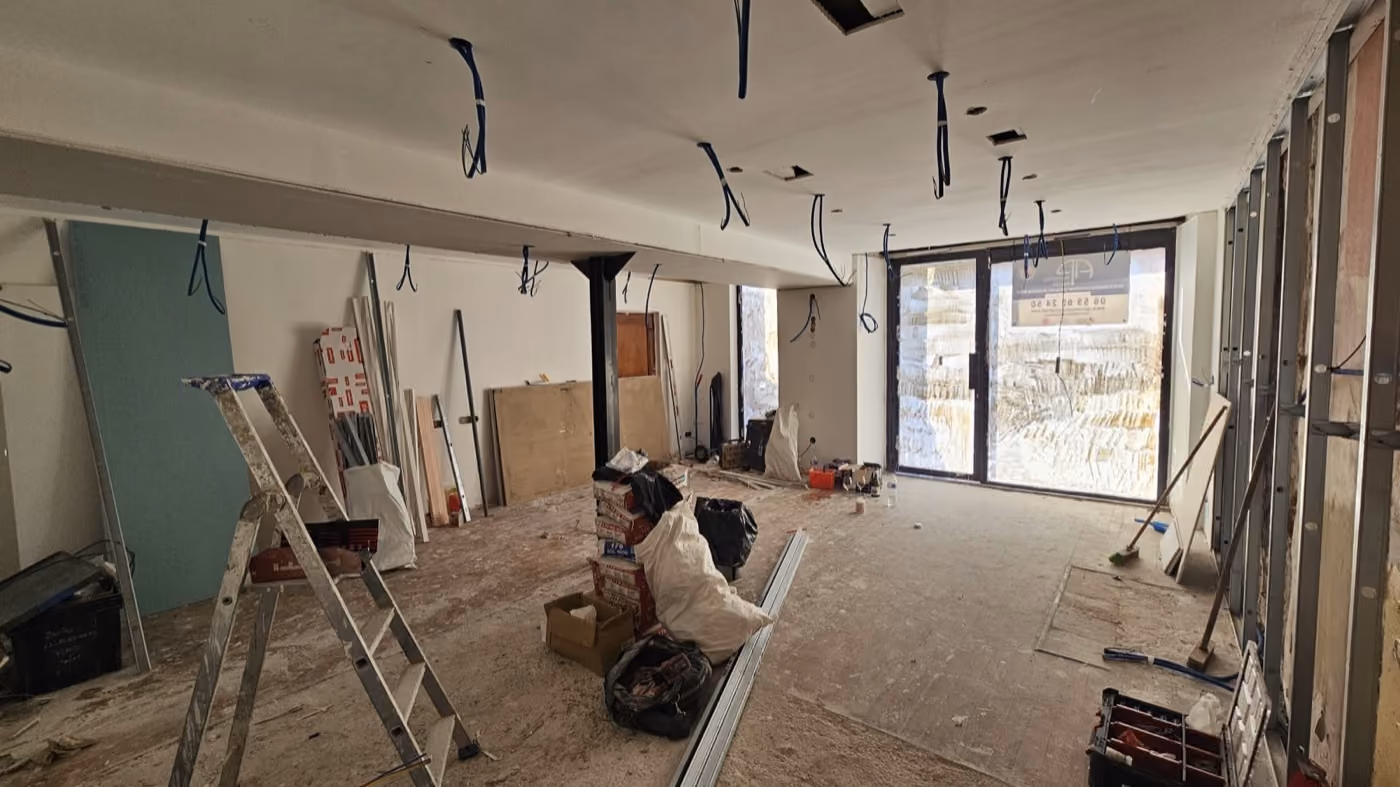 Le local de la future boutique à nu pendant les travaux, câbles au plafond et échelle au milieu du plateau