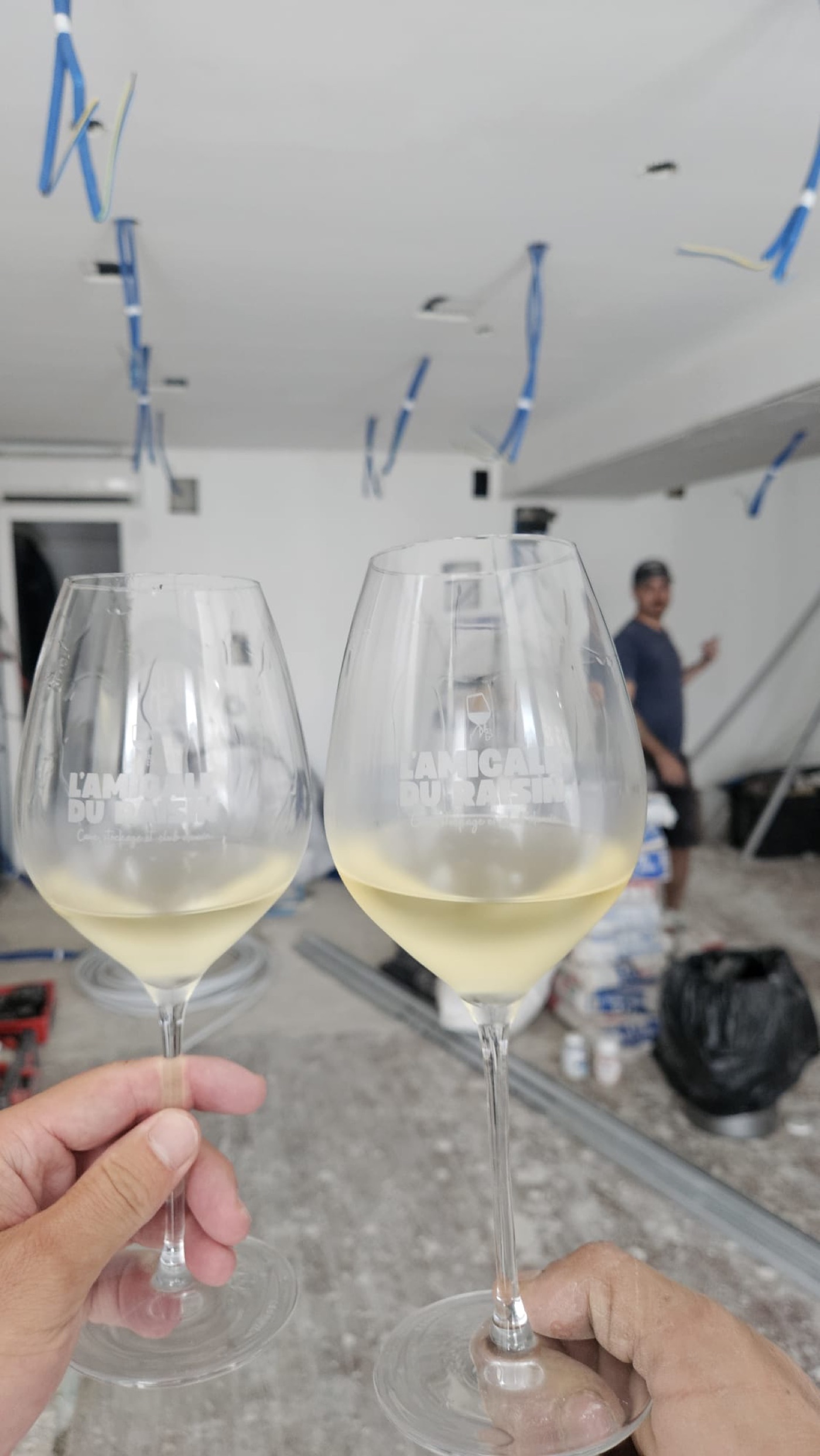 Deux verres gravés L'Amicale du Raisin levés en trinquant dans la future boutique en plein chantier