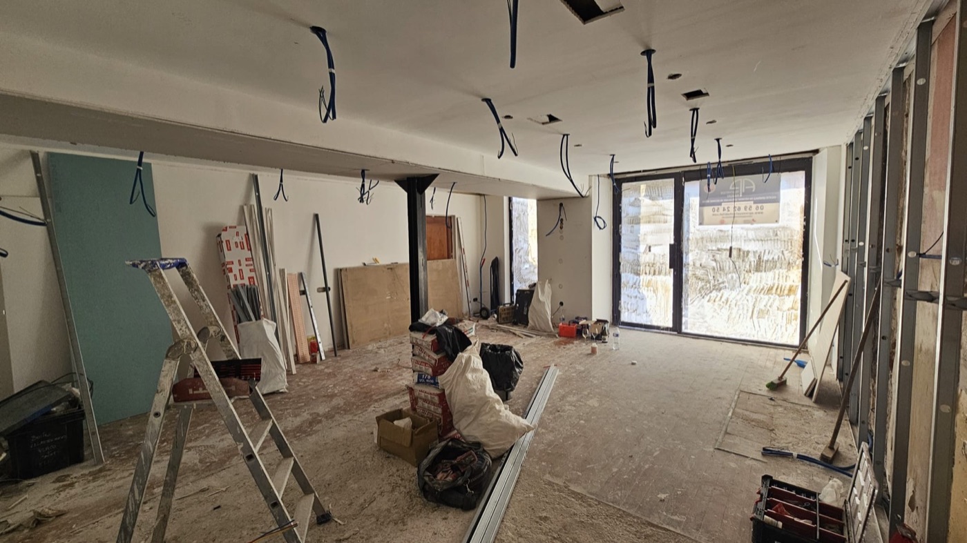 Le local de la future boutique à nu pendant les travaux, câbles au plafond et échelle au milieu du plateau