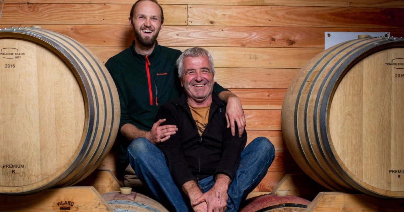 Marc et Thibaut Penavayre souriants entre les barriques de leur chai en bois