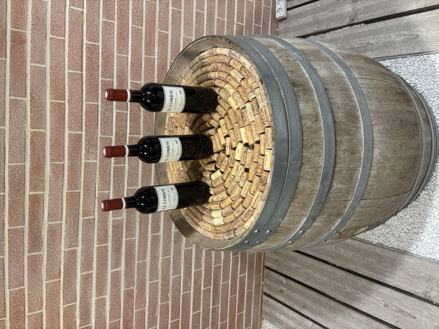 Tres botellas de Le Combal de Cosse-Maisonneuve plantadas en un tonel lleno de corchos